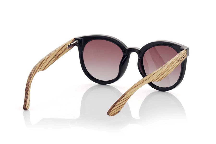 Gafas de Madera Natural de Walnut SOPHIA. Las gafas de sol Sophia son el accesorio perfecto para darle un toque de estilo a tus looks en todo tiempo. Con una montura redondeada en color negro satinado,  las lentes están montadas sobre la montura, lo que le da un toque retro y moderno al mismo tiempo. Las varillas anchas de madera de nogal veteada hacen un contraste armonioso con la montura. Este modelo es un modelo femenino muy atractivo aunque algunos hombres más atrevidos también querrán tener unas, está disponible en dos colores de lentes para que puedas elegir el que mejor se adapte a tus necesidades y estilo. No dudes en hacerte con unas gafas Sophia para proteger tus ojos del sol con estilo.Medida frontal aprox : 142x55mm Venta al Por Mayor y Detalle | Root Sunglasses® 